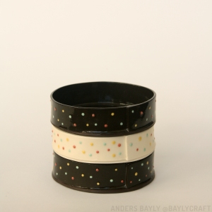 Three stacked dishes. Each is a cylinder 4 inches in diameter and 1 inch tall. Each is either black or white and covered in colourful confetti-like textural dots.